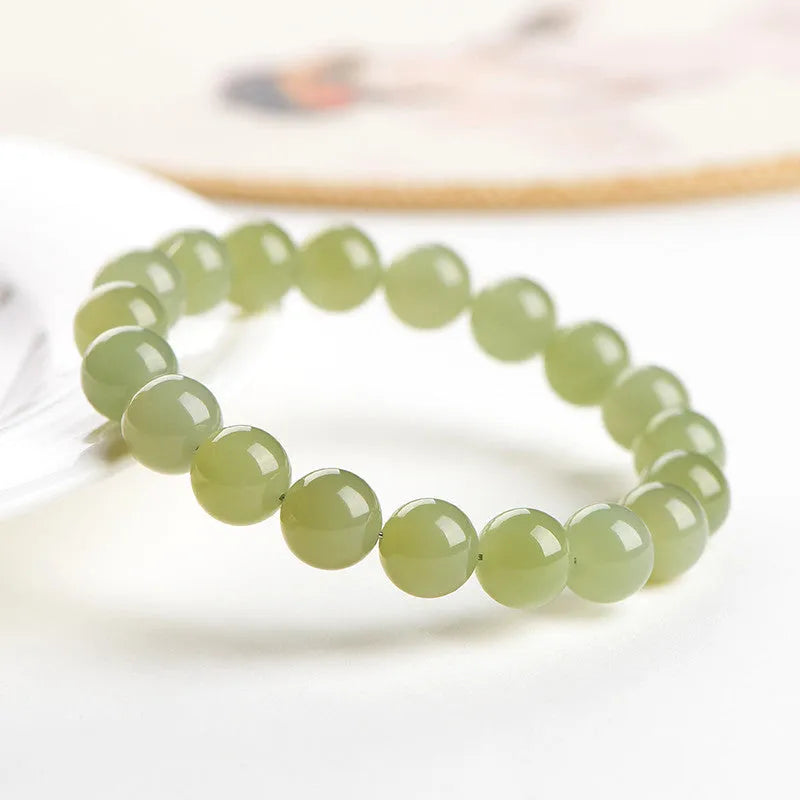 Polished Hetian jade bead bracelet in light or deep clear water colour on a wrist.