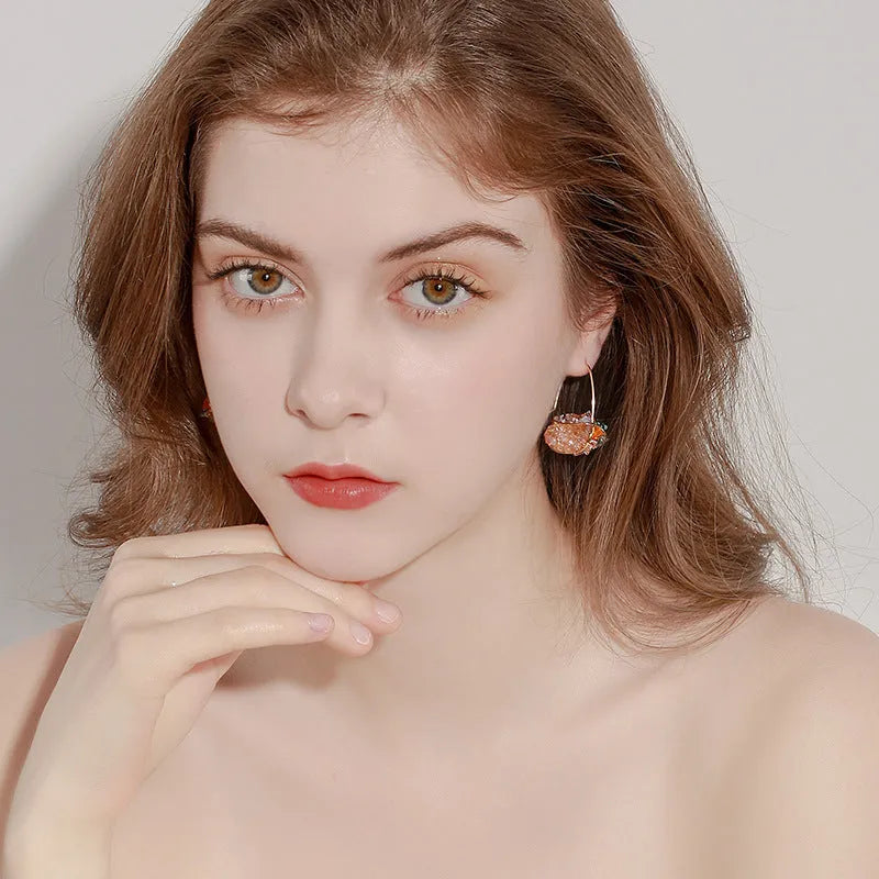 Pair of champagne gold geometric quadrilateral drop earrings on a neutral background