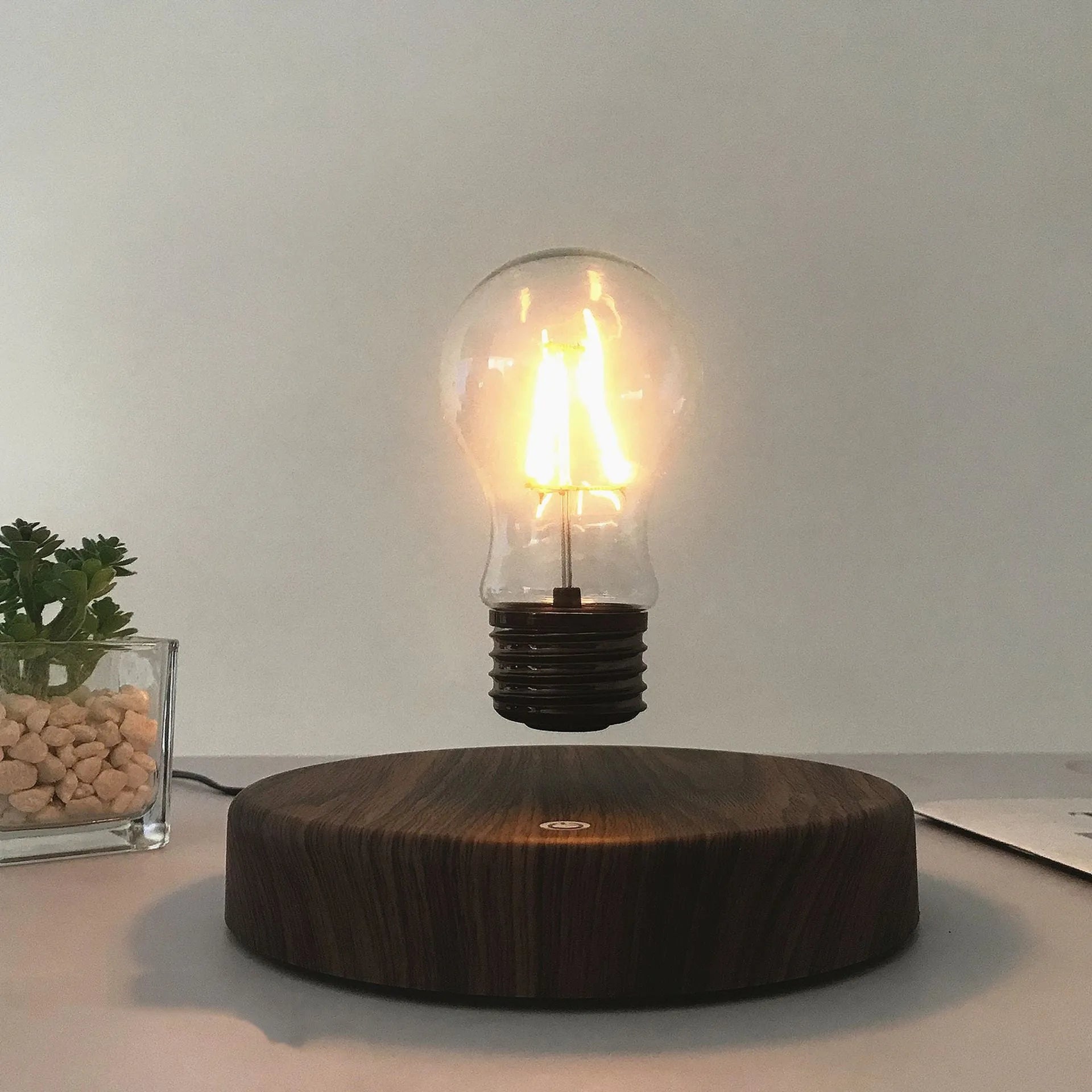 Magnetic levitation desk lamp with floating bulb on a solid wood colour base.