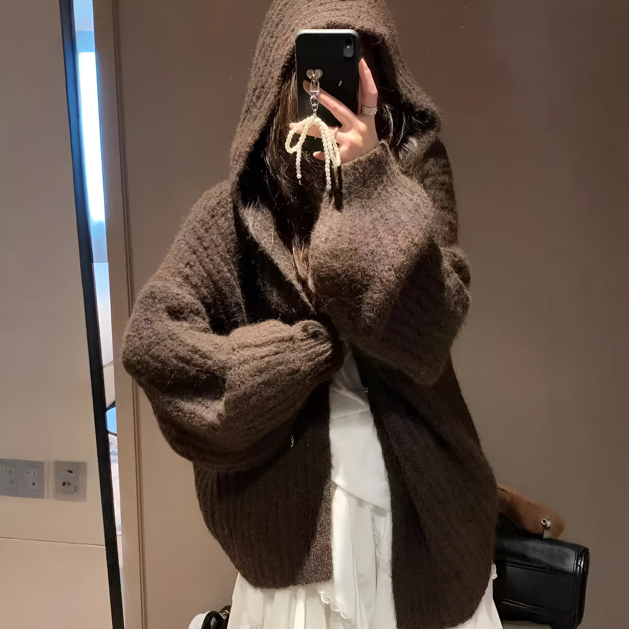 A woman wearing a thick, dark grey hooded cardigan with a loose, longline fit.
