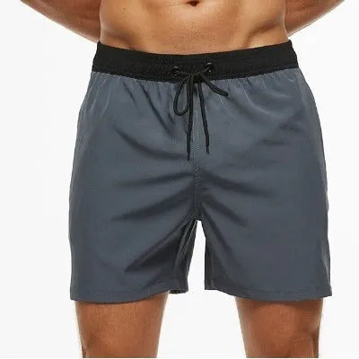 Men's blue training shorts with stitching waist detail, drawstring, and a zipped pocket on the leg.