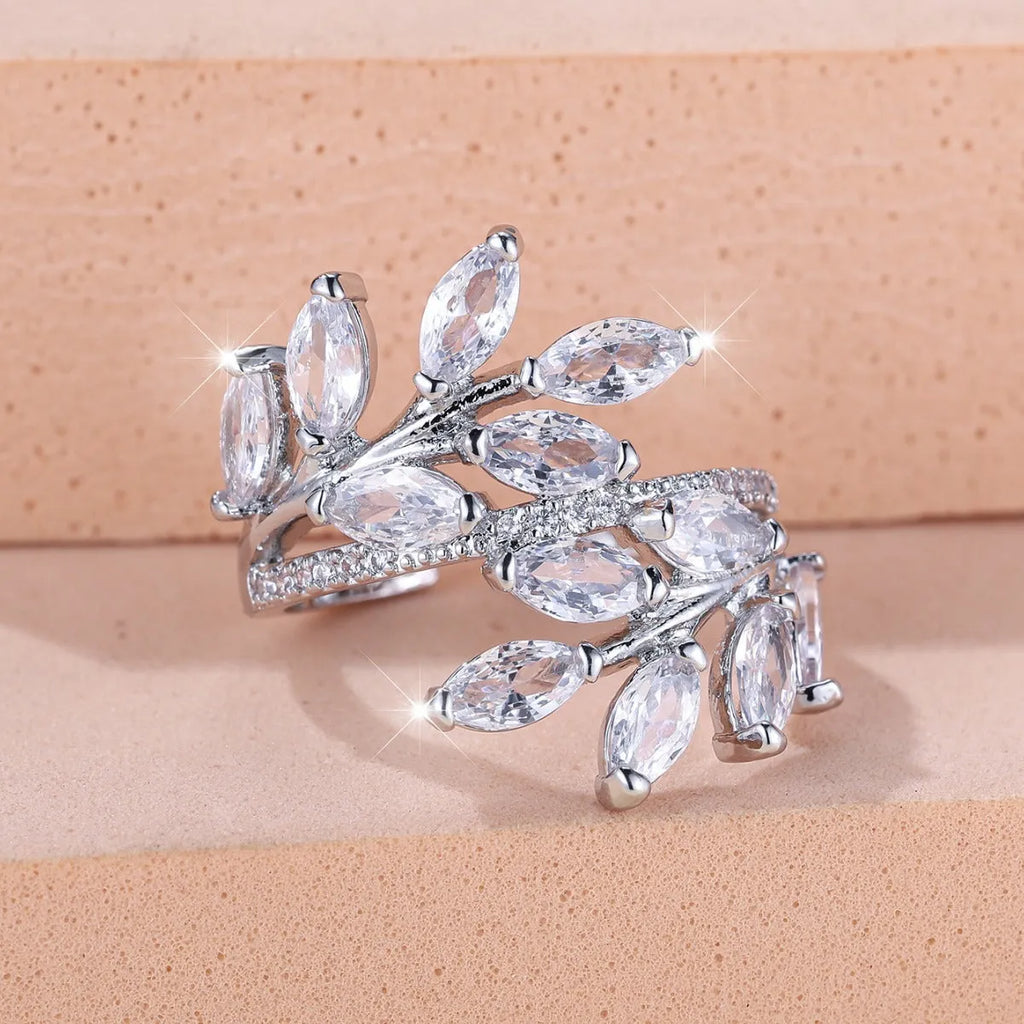 Adjustable open-ended copper ring with leaf design and central blue zircon stone on a finger.