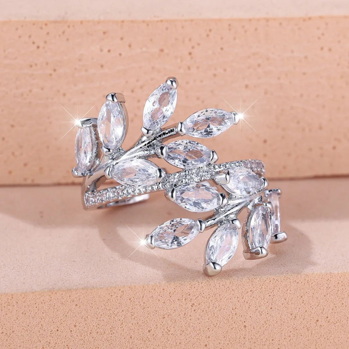 Adjustable open-ended copper ring with leaf design and central blue zircon stone on a finger.