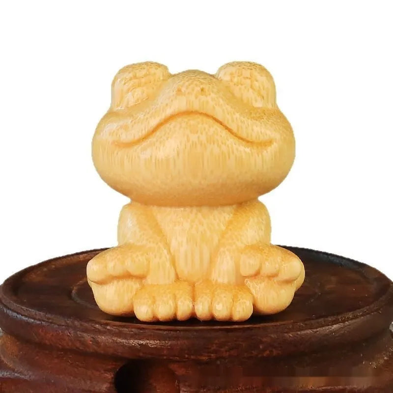 Solid bamboo carving of a smiling cartoon frog ornament, 5cm tall.