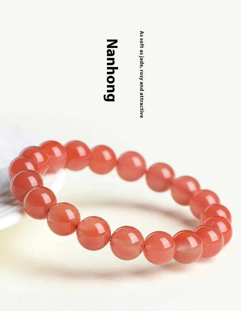 Natural cherry red agate bead bracelet with polished stones on a neutral background, showing single strand and bead detail.