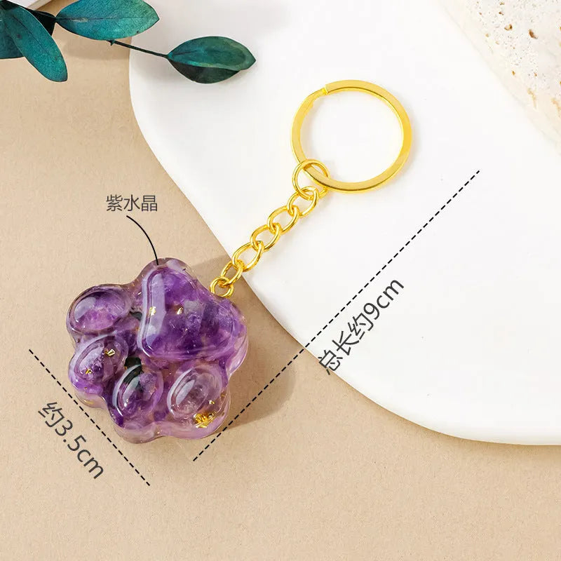Small cat's paw shaped keychain pendant made from a natural pink crystal on a metal ring.