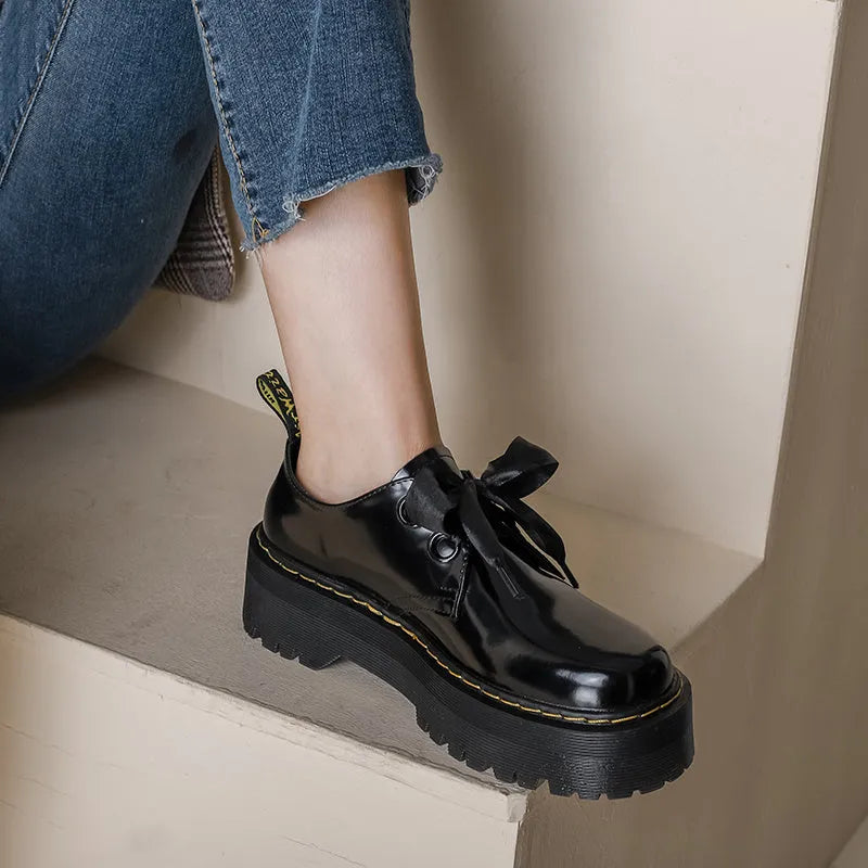 Black women's thick-soled lace-up shoes with decorative white ribbon cross straps.