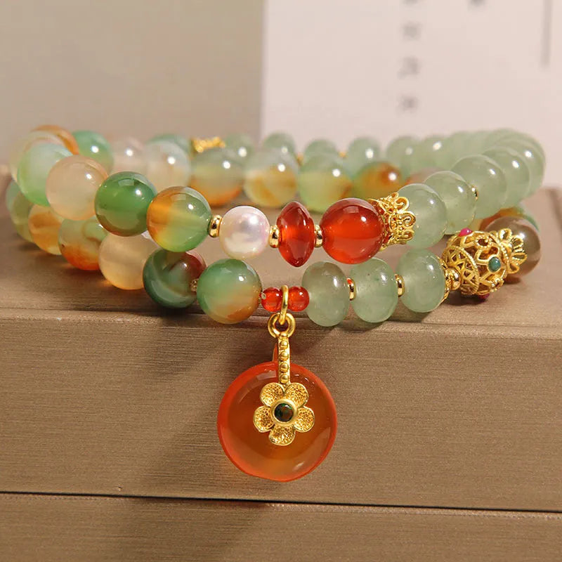 Women's peacock green agate double ring bracelet with safety buckle and rhinestones on a wrist.