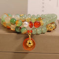 Women's peacock green agate double ring bracelet with safety buckle and rhinestones on a wrist.