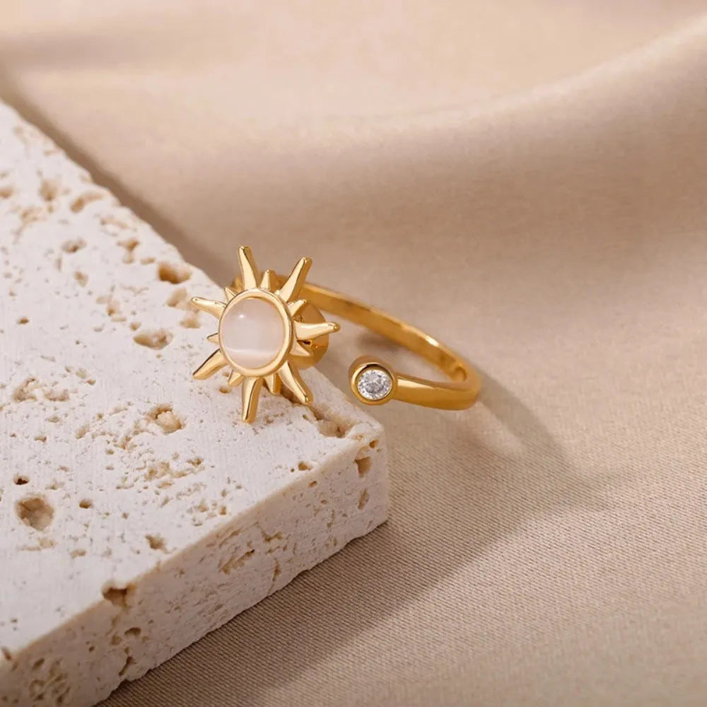 A geometric gold-coloured ring with an adjustable opening, shown rotating on a finger.
