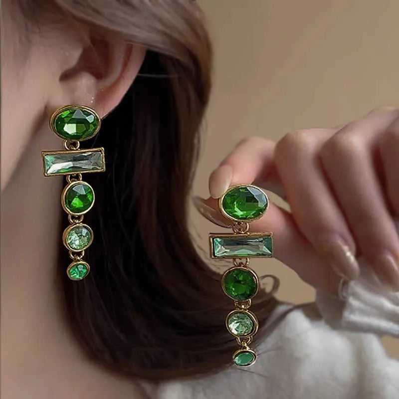 Pair of green gradient geometric ear studs with zircon details and a long tassel, on a white background.