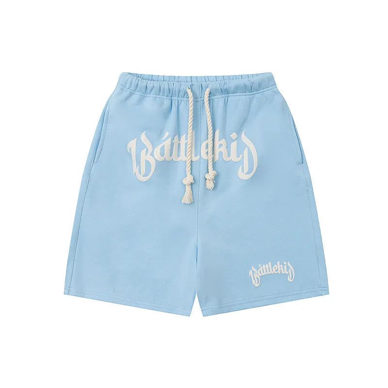 Men's black cotton loose-fit street style cropped shorts on a grey background.