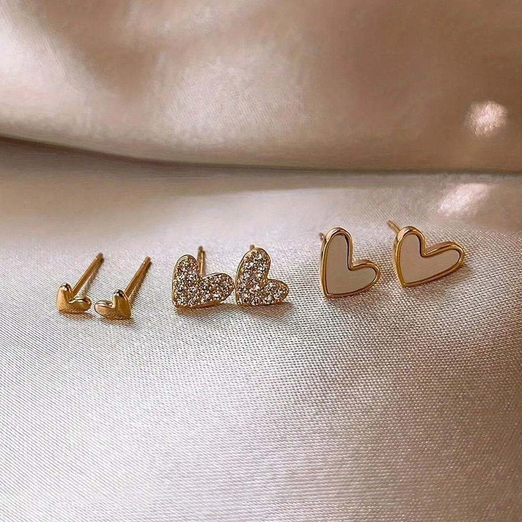 Three pairs of heart-shaped alloy earrings in gold, black, black and white, and pink colours