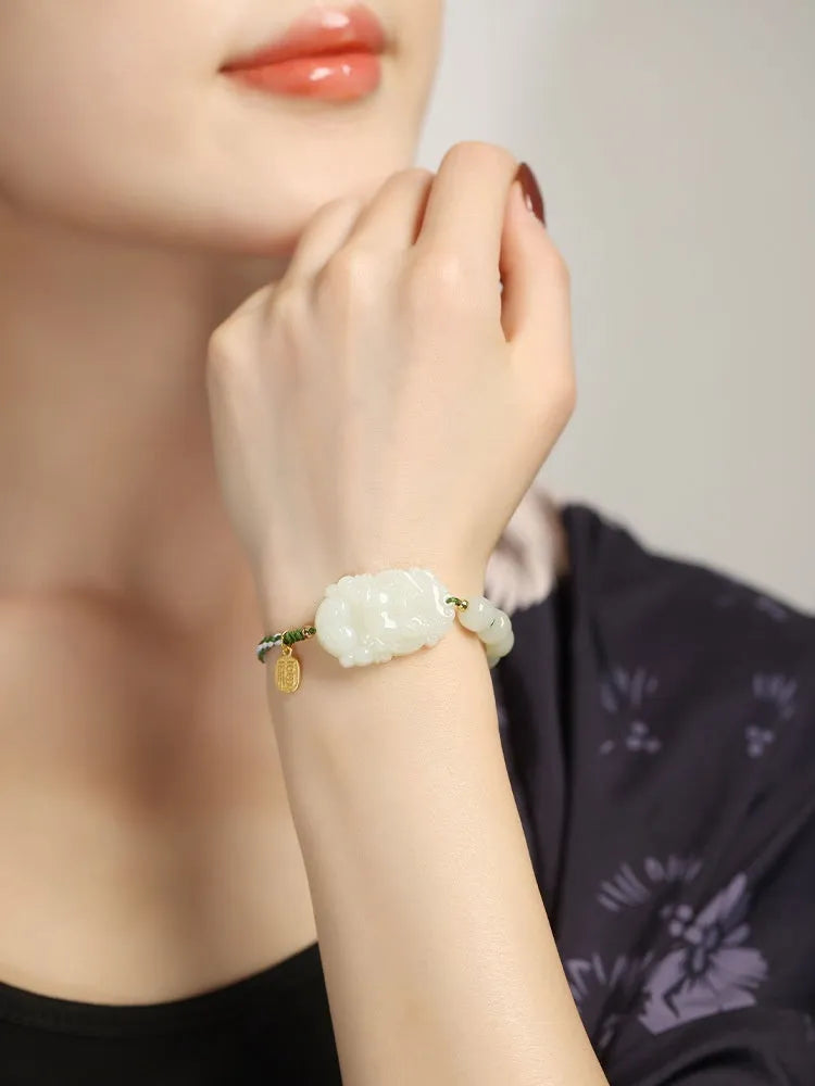 Red rope bracelet with a carved green Hetian jade Rabbit charm and a small S925 silver card on a cotton cord.