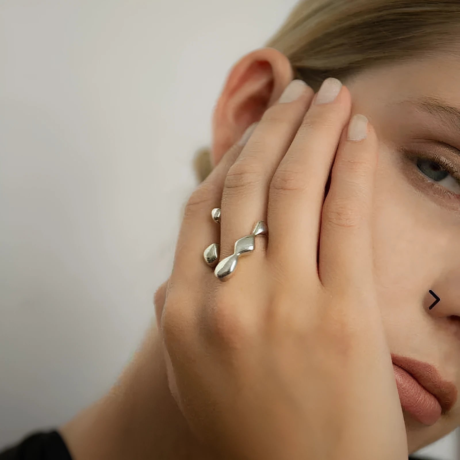 Gold tone brass ring with open circle design and central sphere on a person's finger.