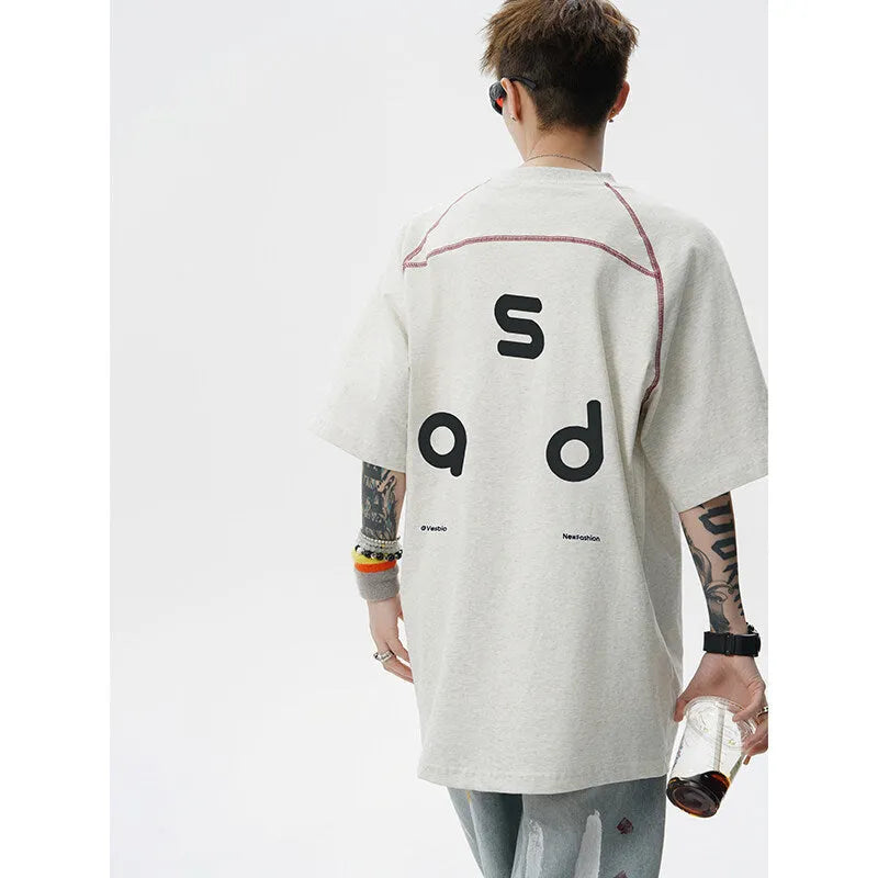 A loose-fit black cotton T-shirt with a white letter print on the front, showing a round neck and short sleeves.