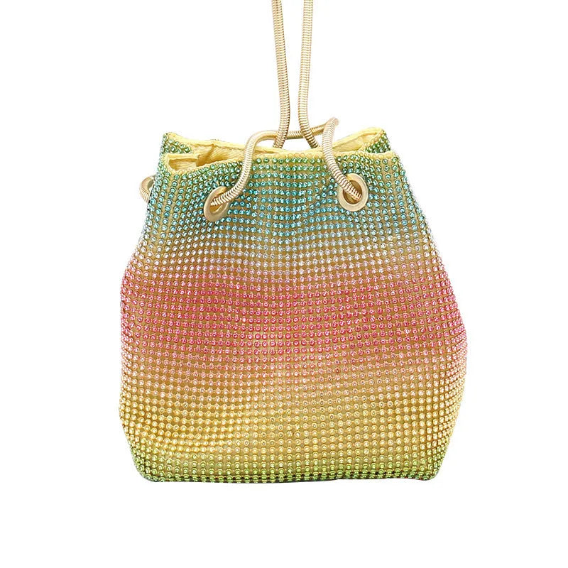Soft rainbow iridescent bucket bag covered in sparkling rhinestones with a shoulder strap on a white background.