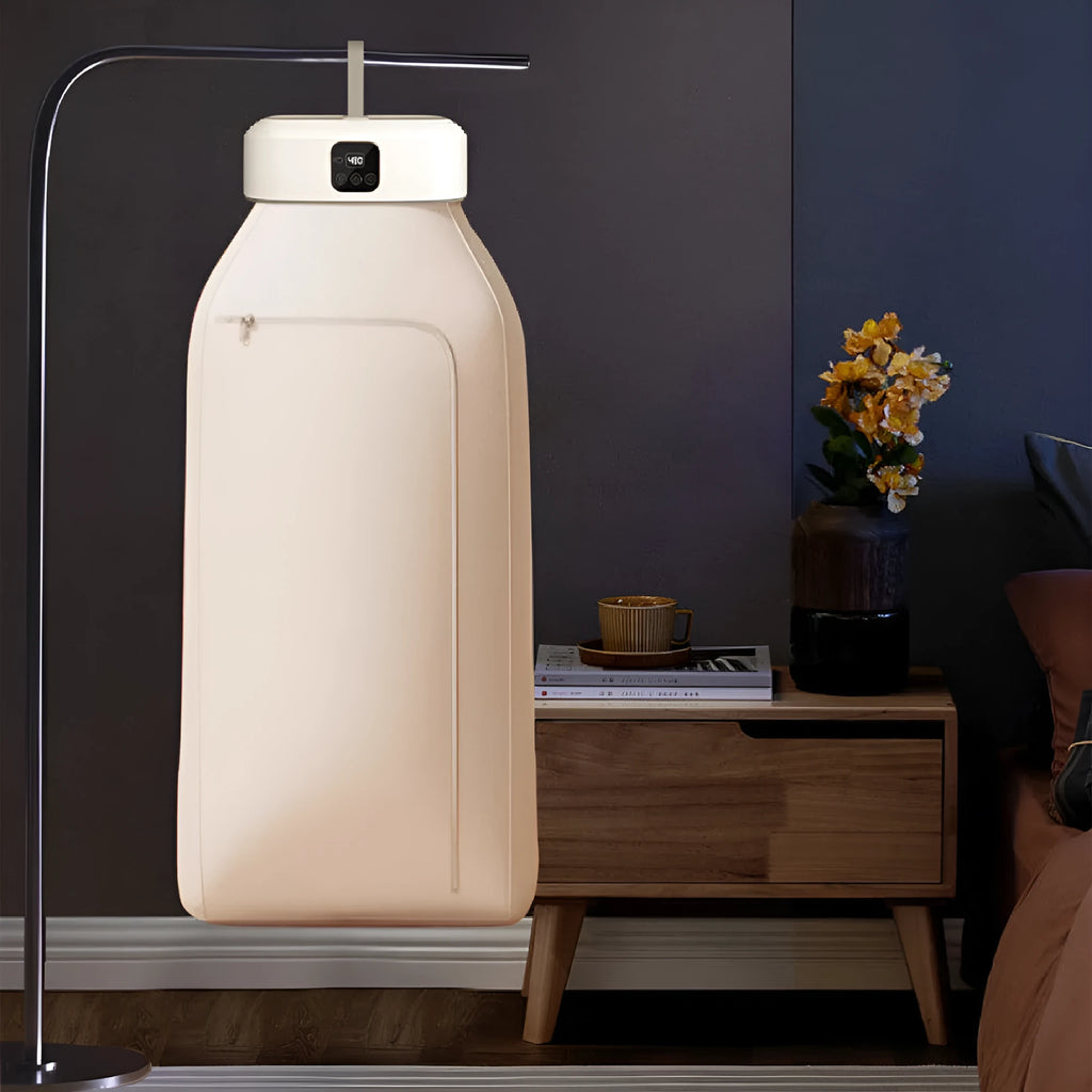 White foldable cylindrical laundry dryer with remote control on a table.