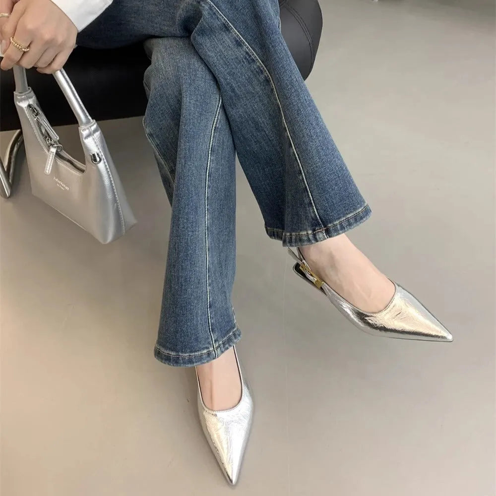 Women's black pointed toe leather strap shoes with a low rubber heel shown from the side.