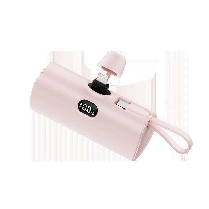 Compact capsule-shaped wireless power bank with a UK plug and digital display, shown in pink.