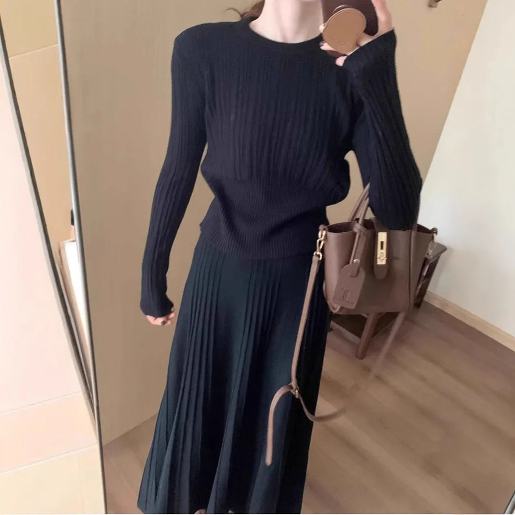 Dark grey knitted women's sweater and skirt set with a raised 3D pattern, laid flat.