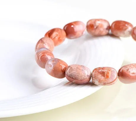 Natural cherry agate bracelet with geometric 10x14mm barrel beads and ruyi details on a wrist.