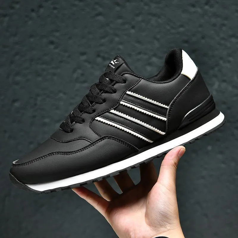 Men's black leather casual shoes with a carved wing pattern design and a white mesh tongue.