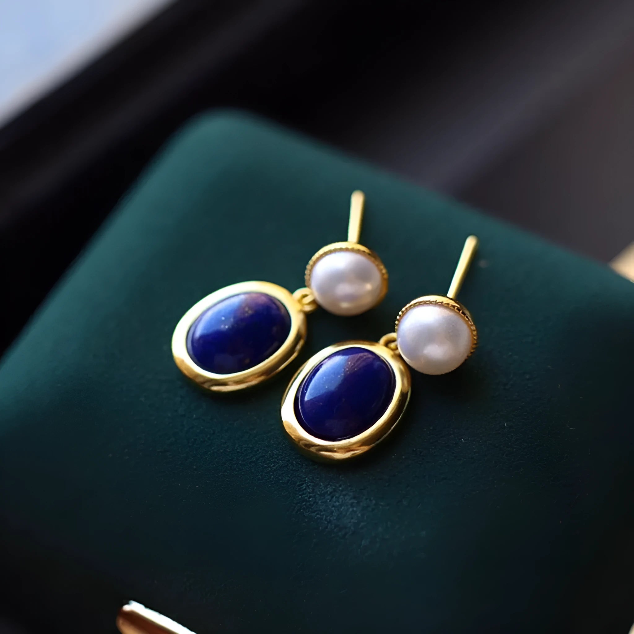 A pair of simple sterling silver earrings with a blue lapis lazuli pearl and auspicious patterns.