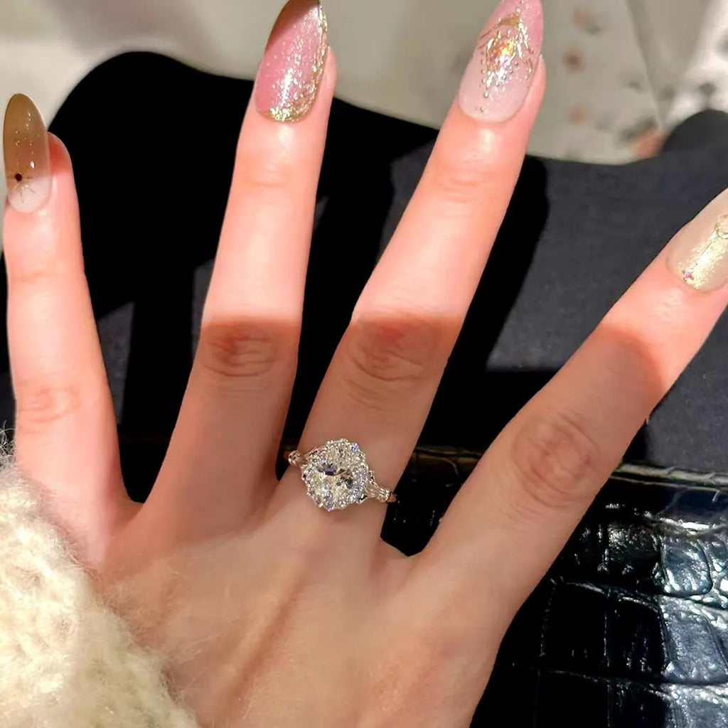Silver geometric ring with an elliptical diamond centre on a model's hand, showing adjustable opening.