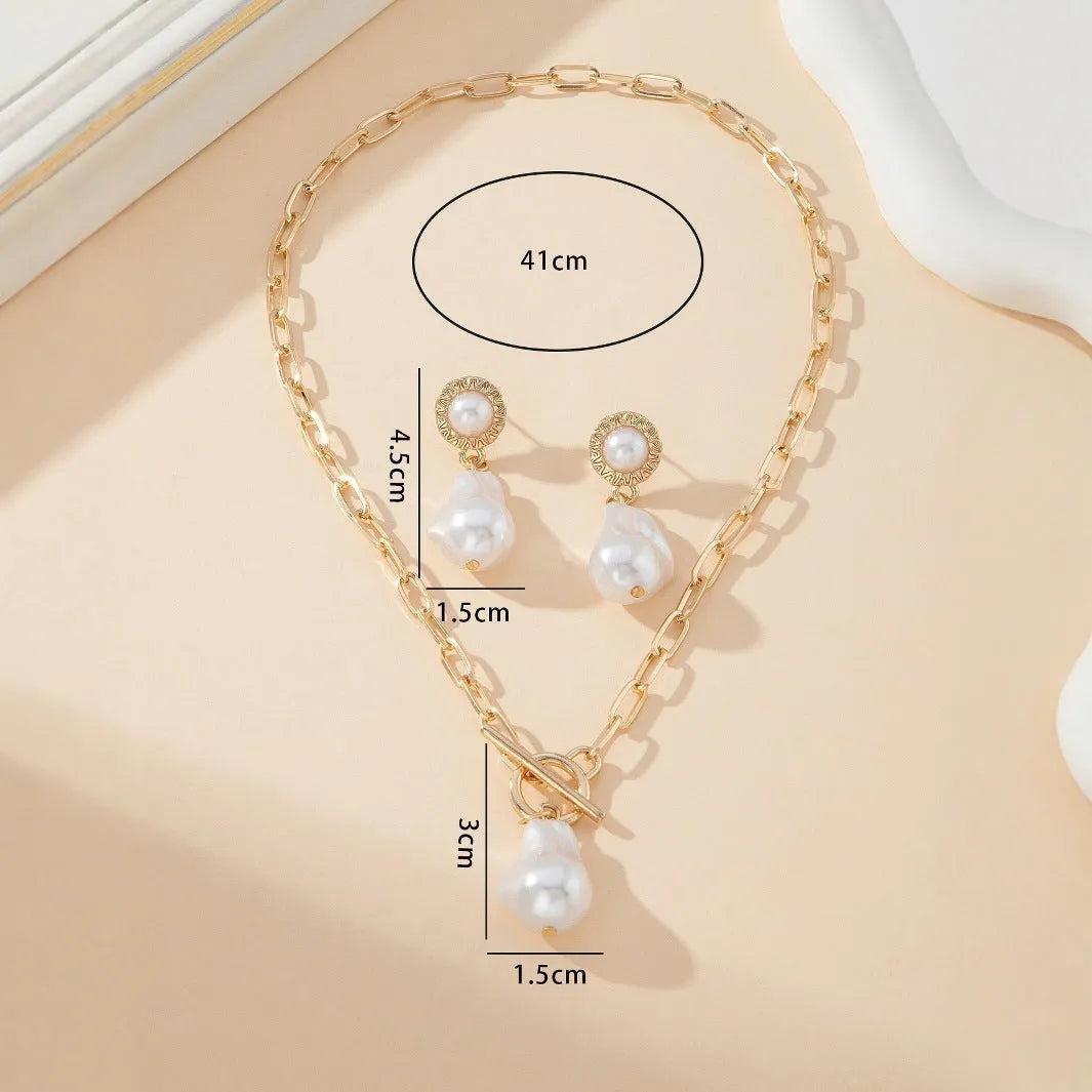 Gold-coloured retro baroque pearl necklace and matching ear studs set on a display.