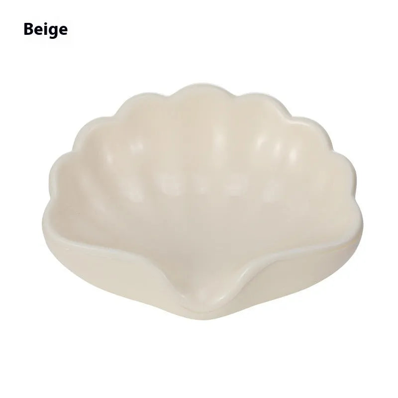 A white or pink plastic shell-shaped soap dish for bathroom counter or shower use.