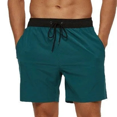 Men's blue training shorts with stitching waist detail, drawstring, and a zipped pocket on the leg.