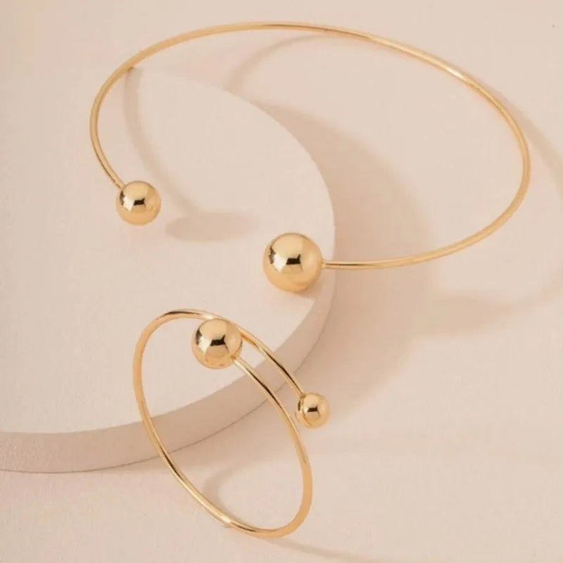 Gold silver ball dislocation thin open-end bangle bracelet with matching necklace ornament on white background
