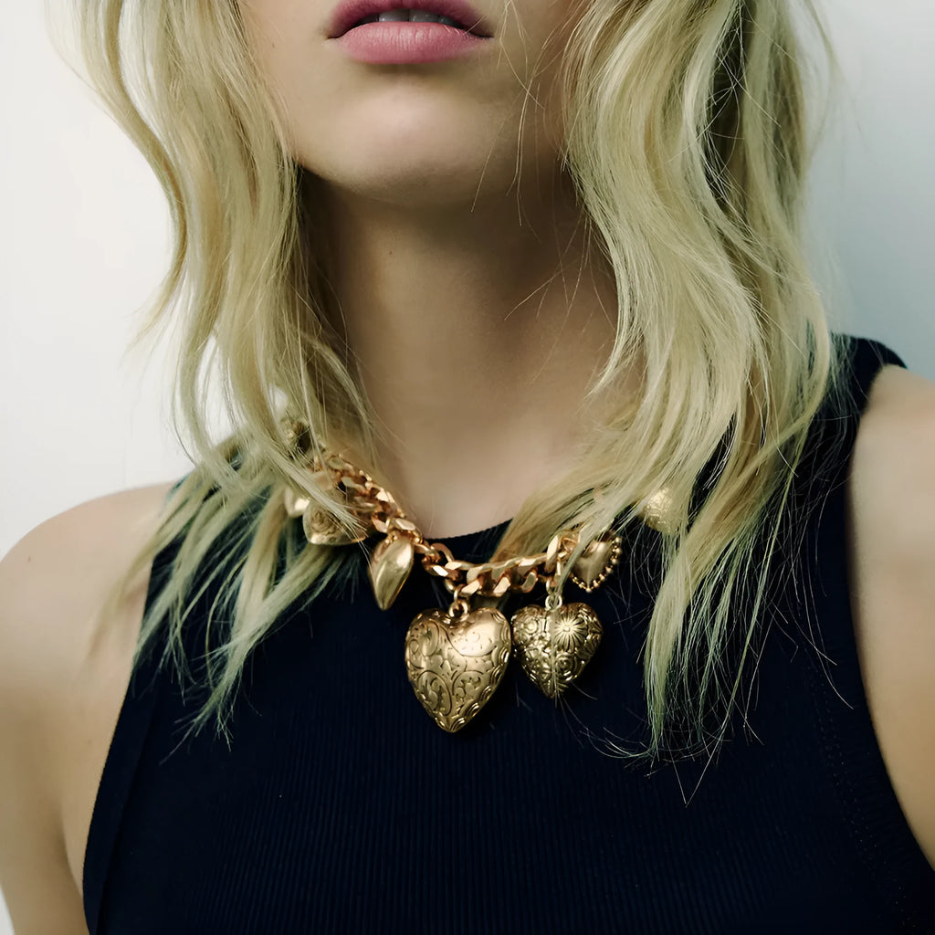 Carved heart-shaped pendant necklace on a metal chain, shown in gold and white K colour options.