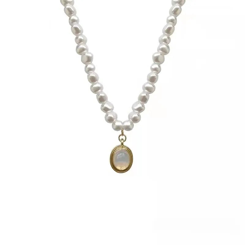 Vintage geometric pearl necklace with adjustable chain on a dark background.