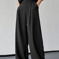 Black men's casual trousers with vertical stripes and front pleats on a hanger.