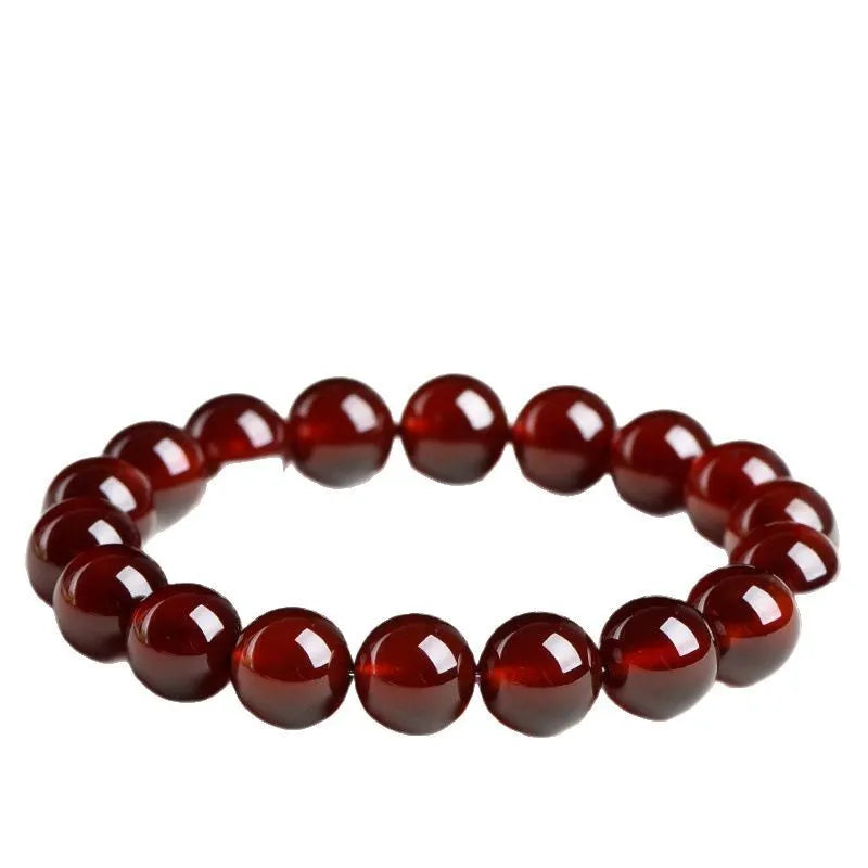 Unisex orange red garnet ball bracelet with crystal beads and a metal Ruyi charm on a wrist.