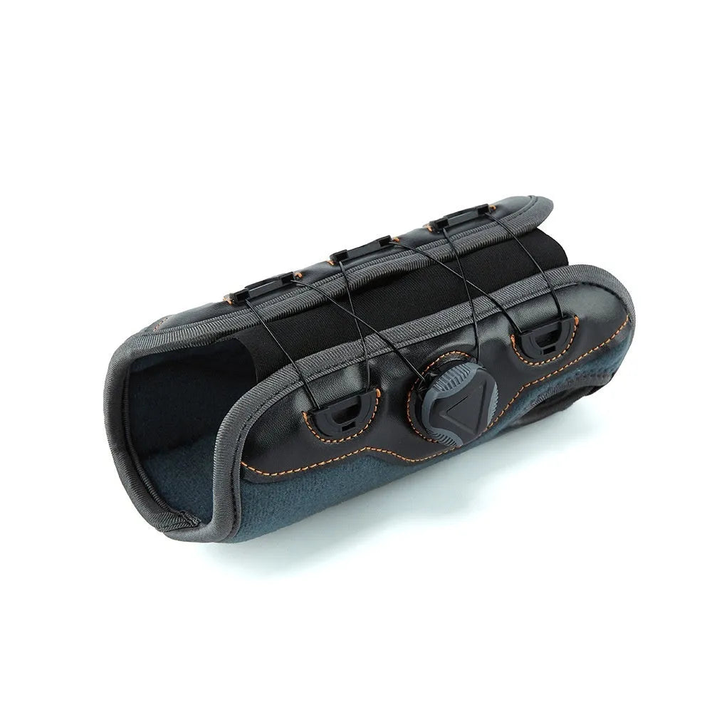 Black adjustable athletic wristguard with rotating pressure system on a flat surface
