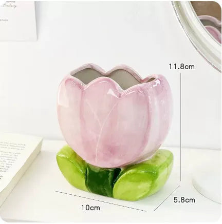 Ceramic pen holder box with floral decoration on a desk, holding pens.