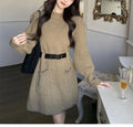 Women's loose-fitting, high-waist knitted dress with long sleeves in beige colour with a black belt.