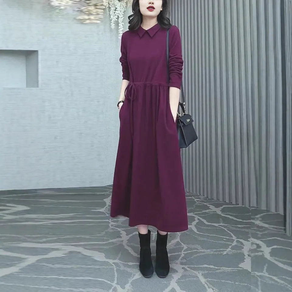 Purplish red women's long-sleeve maxi dress with extra-long cuffs and urban commute style on a hanger.