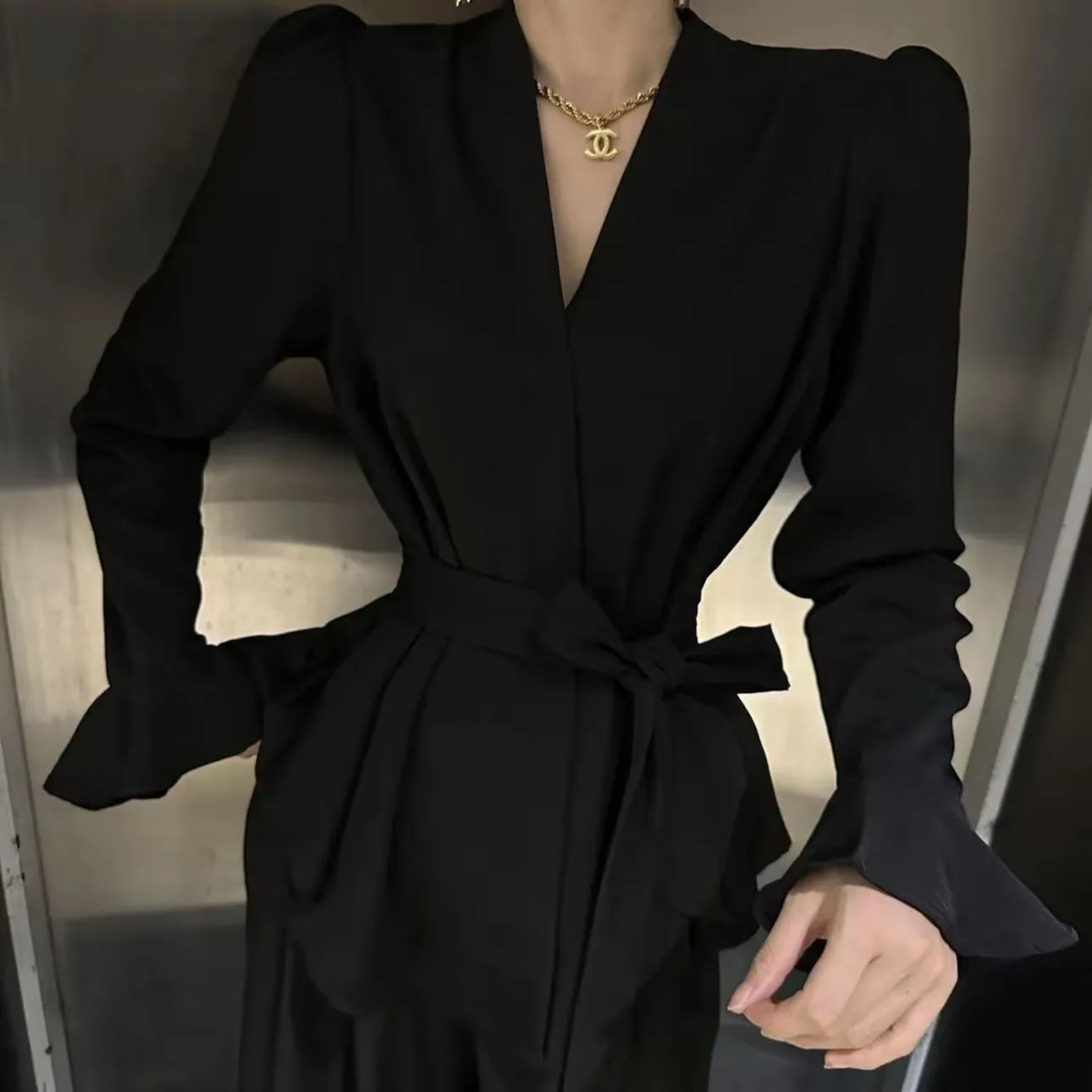 Women's black long sleeve shirt with an irregular collar and a tie closure at the neck.