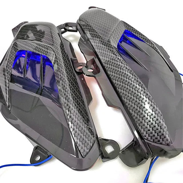 Pair of YAMAHA NMAX side replacement lamps with LED lights and carbon fibre pattern, showing blue illumination option.