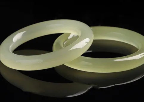 Ice silk jade round bar bracelet on a wrist, showing its smooth, continuous loop and polished stone finish.