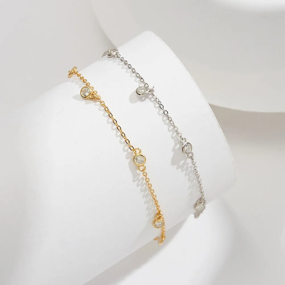 Close-up of a women's geometric zirconium pendant anklet on a sterling silver chain.