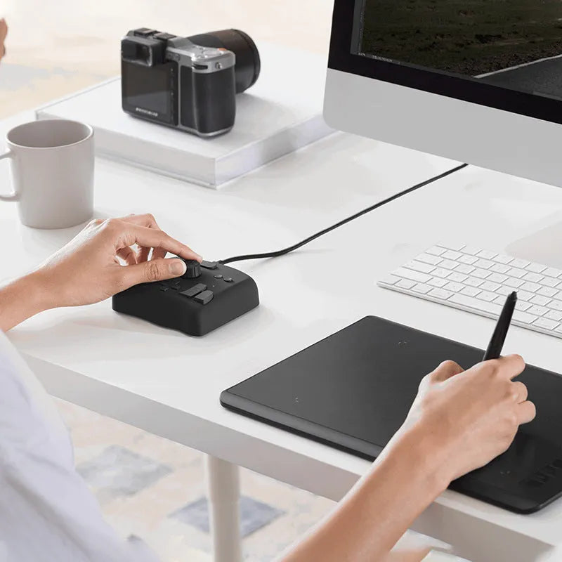 TourBox NEO video editing controller in black, showing its compact size and array of dials and buttons.