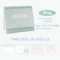 Cream desk calendar with coil binding showing year-round layout, paper pages, and ring binding on a desk surface