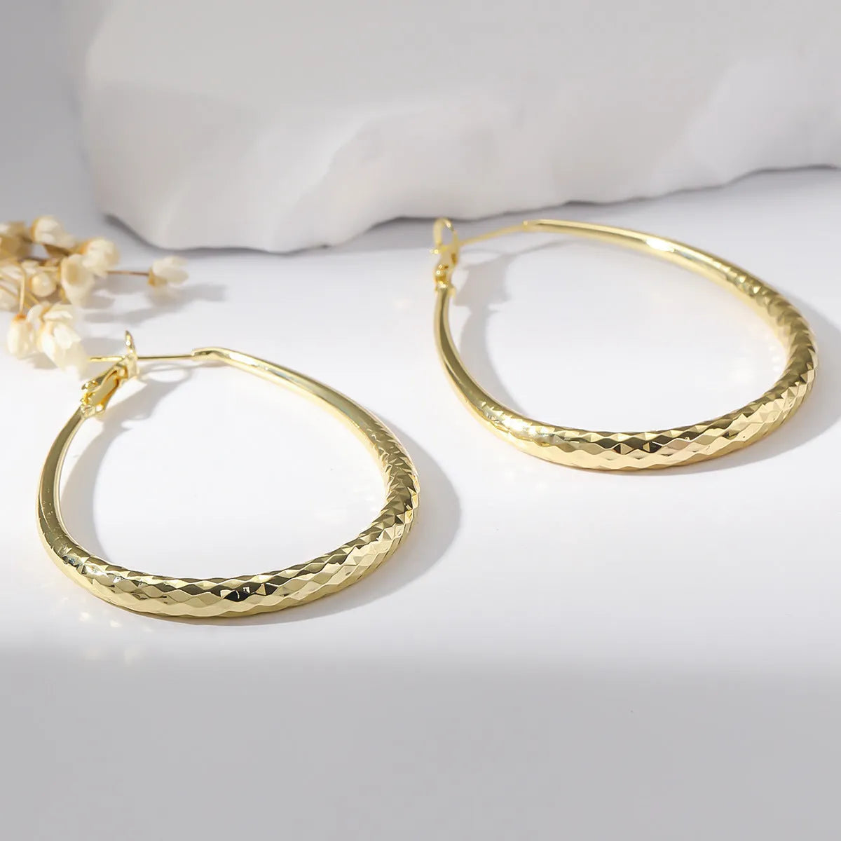 Gold glossy egg-shaped spring fastener earrings made from hypoallergenic copper, unisex geometric design