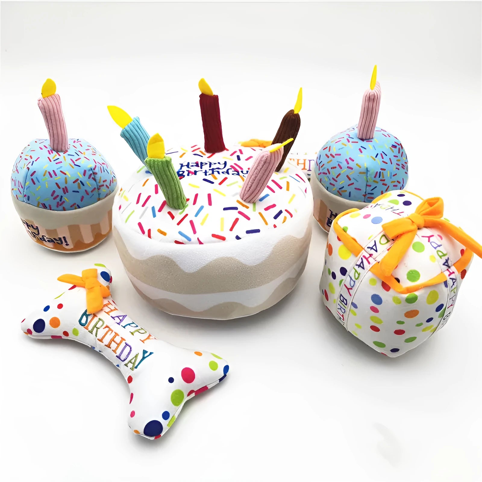 Four soft plush dog birthday toys: large cake, small cake, gift box, and bones on neutral background