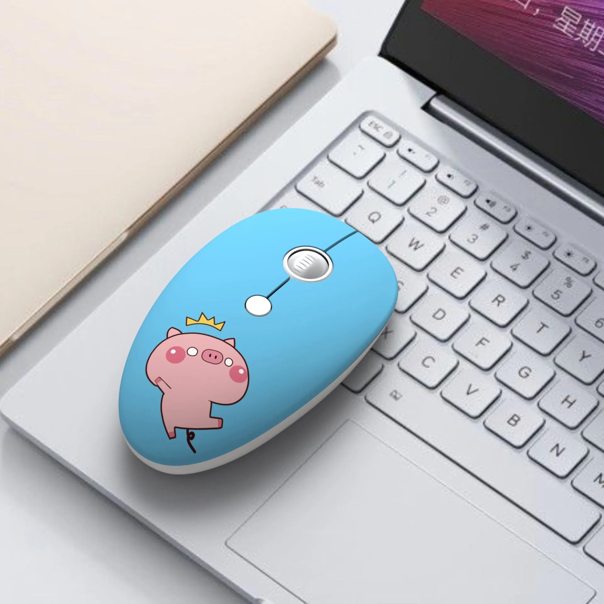 Colourful wireless mouse with cartoon animal designs next to laptop showing compact size
